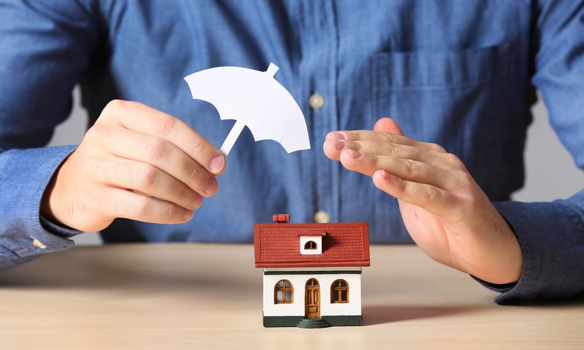 Hands and umbrella protecting home