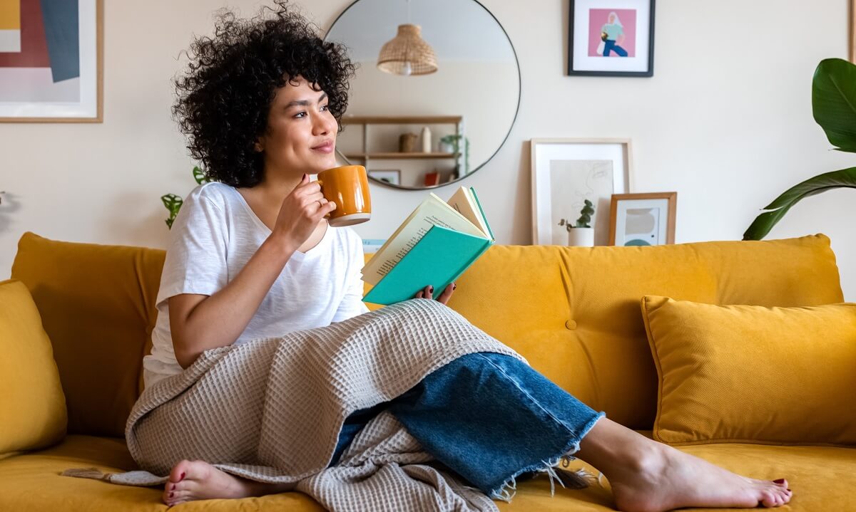 Women enjoying a book and cup of coffee in warm home
