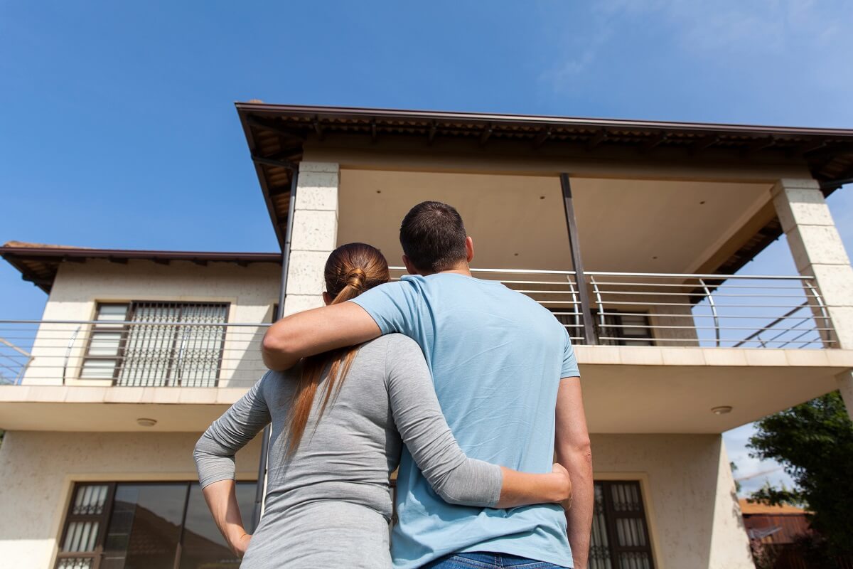 Couple standing outside admiring new home