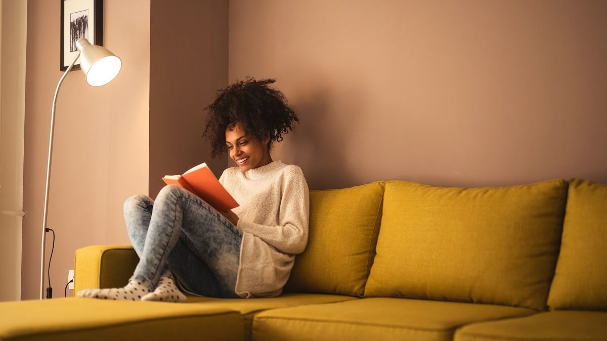 Reading a book in the living room under a lamp
