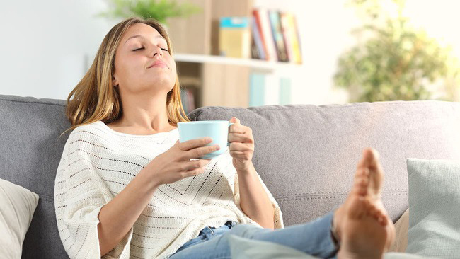 Woman relaxing on couch with feet up and a cup of coffee
